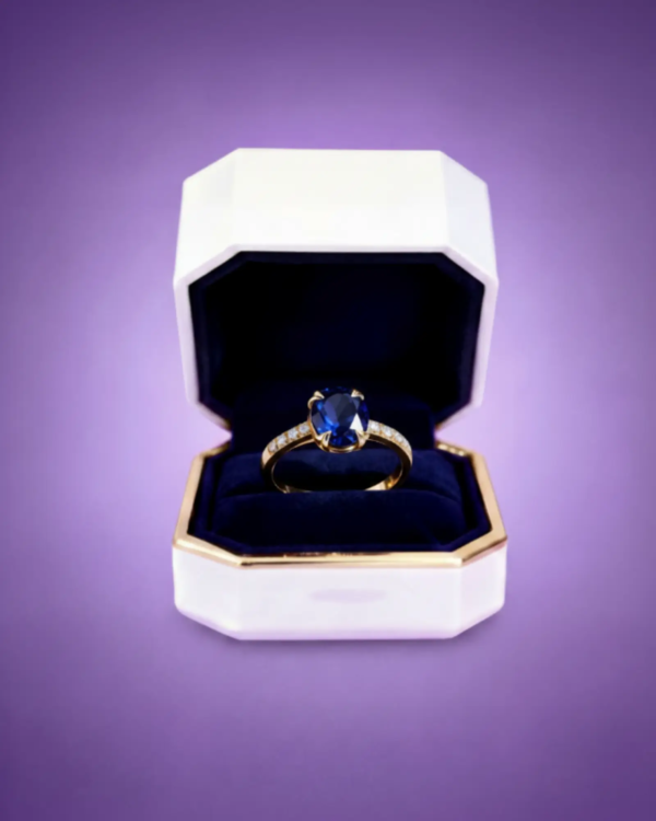Gold ring with deep sapphire gemstone displayed inside a luxury jewelry presentation box.