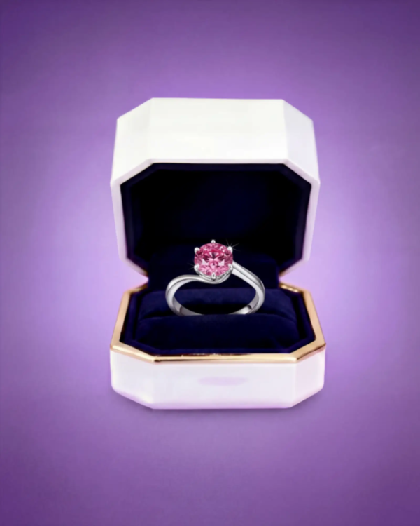 Pink moissanite engagement ring displayed in an Amethyst jewelry box with velvet interior.