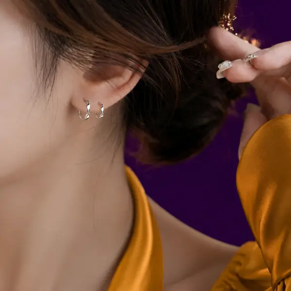 Woman wearing silver small hoop earrings, close-up on ear