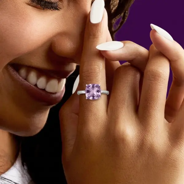 Solitaire amethyst ring worn by Sandra, close-up smiling with hand near face